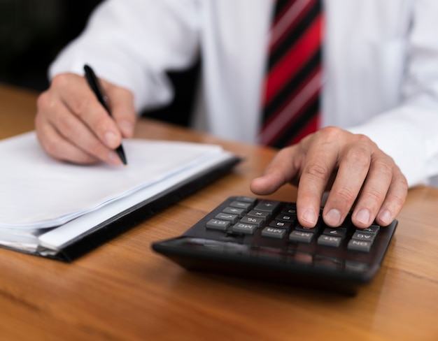 Professional man typing numbers on calculator