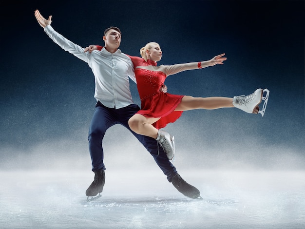 Professional man and woman figure skaters performing show or competition on ice arena