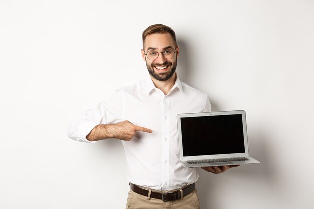 Professional manager showing webpage on laptop screen, pointing at computer, standing  