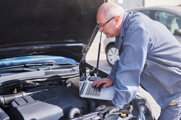 Foto gratuita meccanico professionista che utilizza la tecnologia contemporanea al lavoro