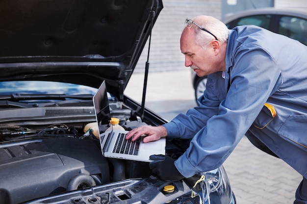 Foto gratuita meccanico professionista che utilizza la tecnologia contemporanea al lavoro