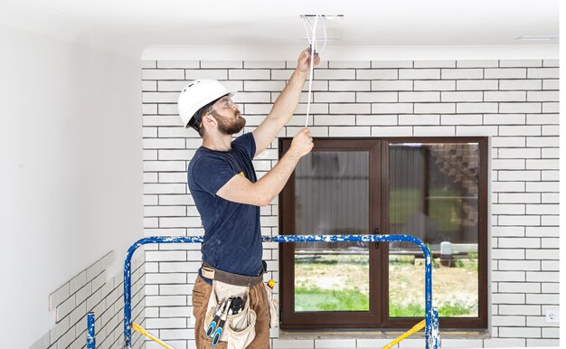 Professional in overalls with tools on the background of the repair site full length. Home renovation concept.