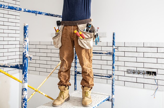 Professional in overalls with tools on the background of the repair site.