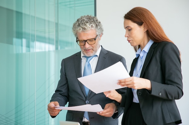 Professional partners discussing project and holding papers in conference room