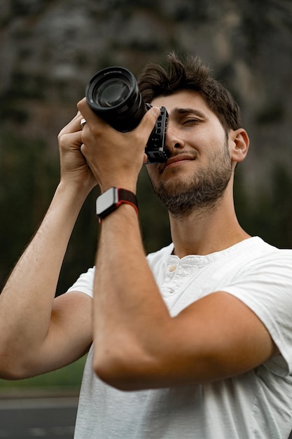 Профессиональный фотограф фотографирует. молодой человек с фотоаппаратом. мужчина фотографирует профессиональной камерой на природе.