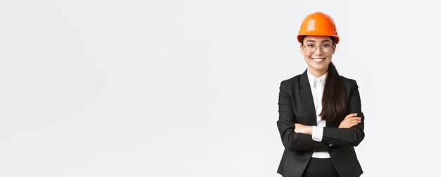 Professional smiling asian businesswoman in safety helmet and suit cross arms and looking confident selling new buildings Construction manager engineer showing around greeting investors