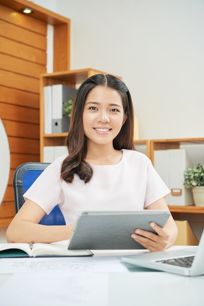 Donna sorridente professionale con la compressa allo scrittorio