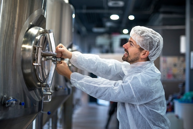 Professional technologist opening industrial tank in production plant