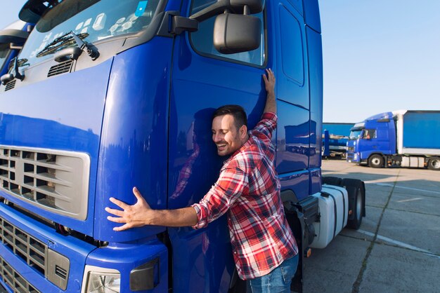 Professional trucker driver hugging his truck cabin loving his job