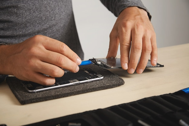 Professional uses plastic opener tool to unplug screen cables from motherboard of smarthone and deattach it to replace