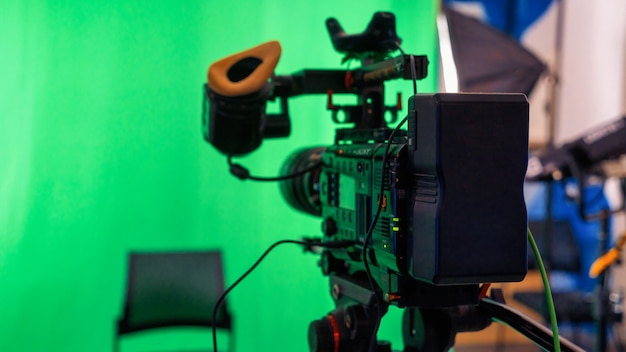 Professional video camera on a stand with green chromakey in a studio