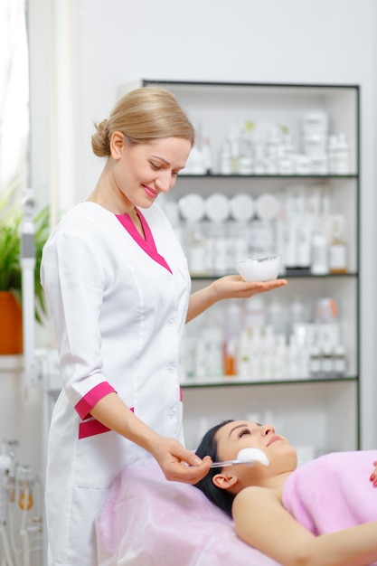 Professional woman applying cream on her face to another woman