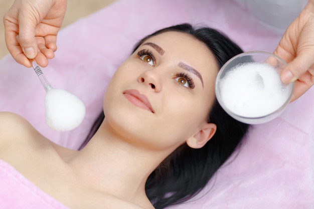 Professional woman applying cream on her face to another woman