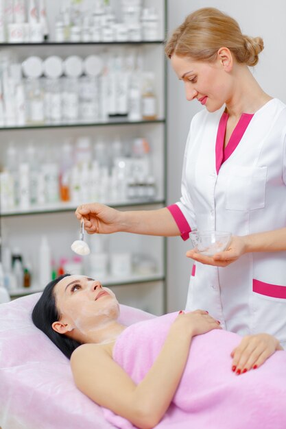 Professional woman applying cream on her face to another woman