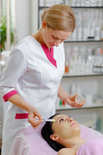 Professional woman applying green cream with a brush