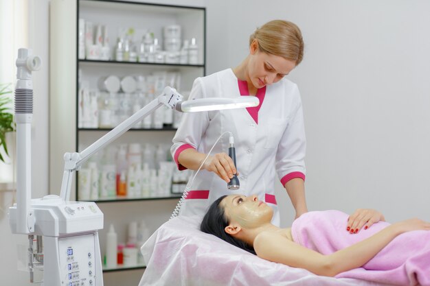 Professional woman applying green cream with a brush