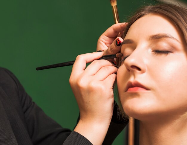 Professional woman making up girl's eyes