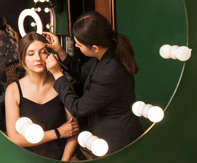 Professional woman making up girl's eyes