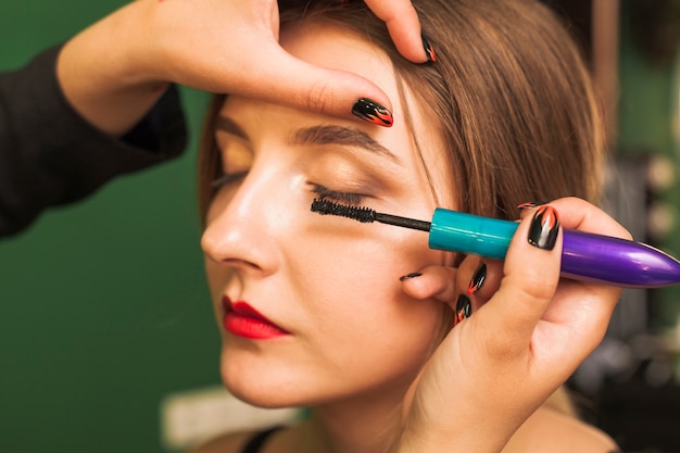 Professional woman making up girl's eyes