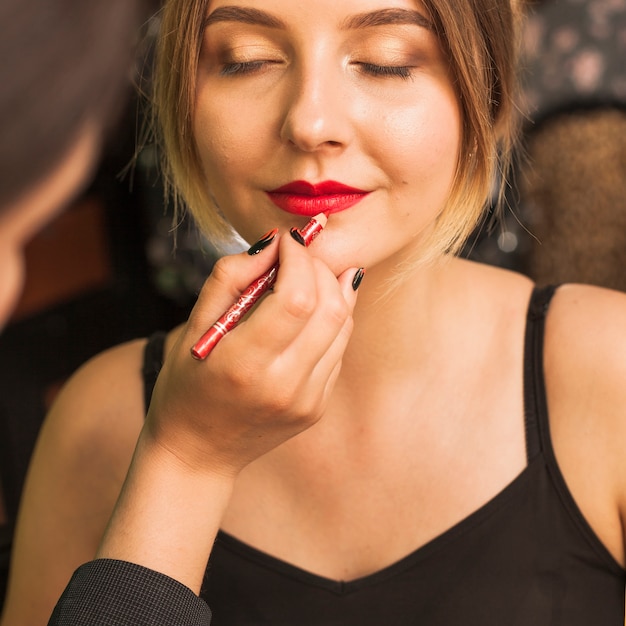 Donna professionale che compone le labbra della ragazza