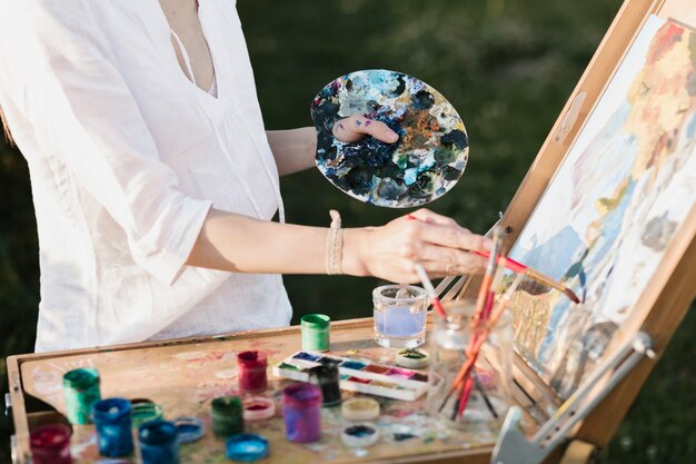 Professional woman painting in the nature