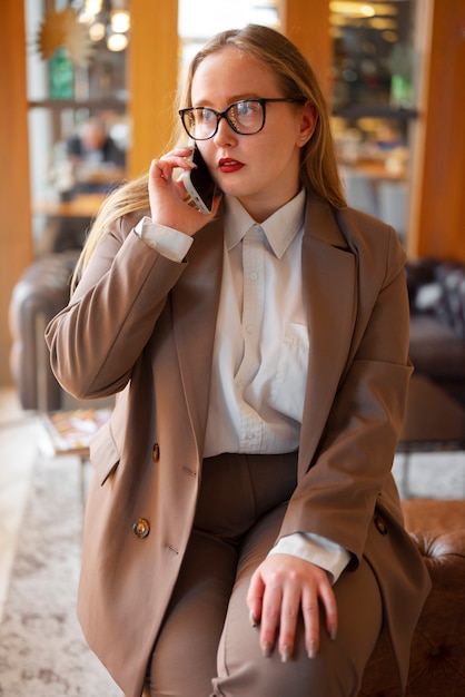 Professional woman in stylish suit at the office using smartphone