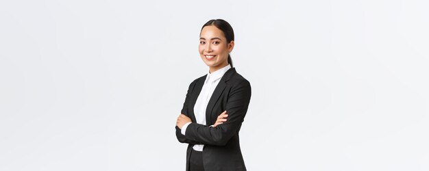 Профессиональная молодая азиатская женщина-предприниматель, агент Real Eastate в костюме, скрещенная на груди и уверенно смотрящая в камеру. Успешная деловая женщина, ведущая бизнес.