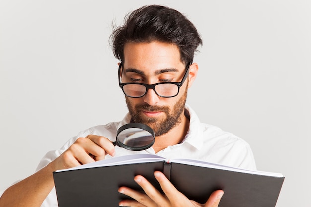 Foto gratuita giovane uomo d'affari leggendo con lente di ingrandimento e bicchieri
