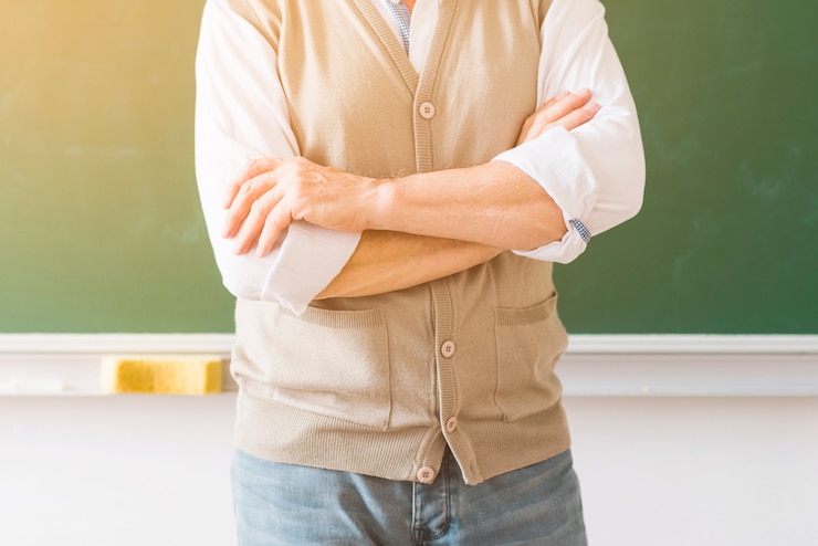 無料Photo 腕を組んで黒板に対して立っている教授