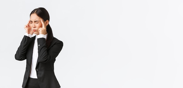 Profile of asian businesswoman in black suit having migraine touching temples and grimacing from pai