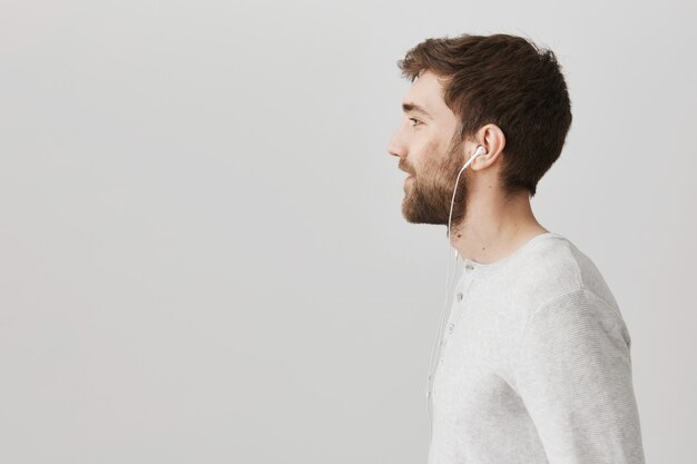 Профиль бородатого красивого парня, слушающего музыку в наушниках