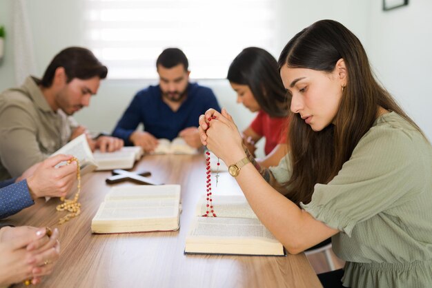 Profile of a beautiful hispanic woman with a lot of faith praying on a religious group. Young catholic woman holding a rosary and asking for forgiveness