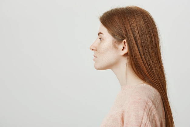 Profile of beautiful redhead woman with freckles looking left