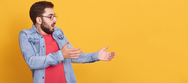 Profile of emotional charismatic man looking ahead, raising arms, having impressed facial expression, opening mouth and eyes widely