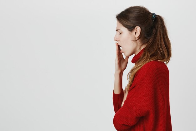 Profile of exhausted woman yawning, cover opened mouth with hand