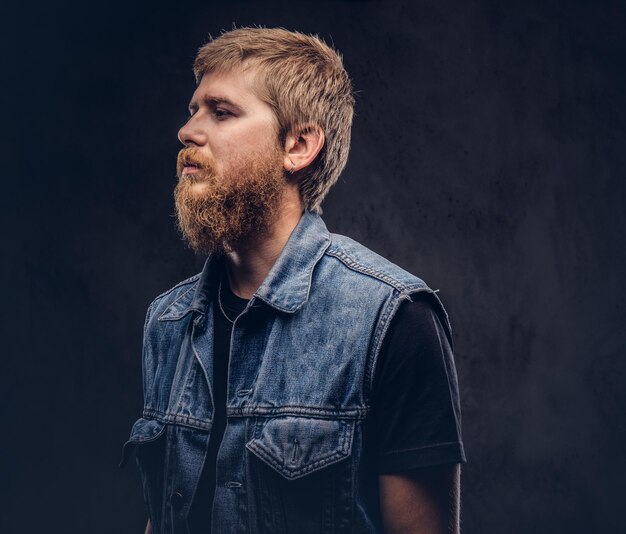 Profile of a hipster guy dressed in jeans jacket. Isolated on a dark background.