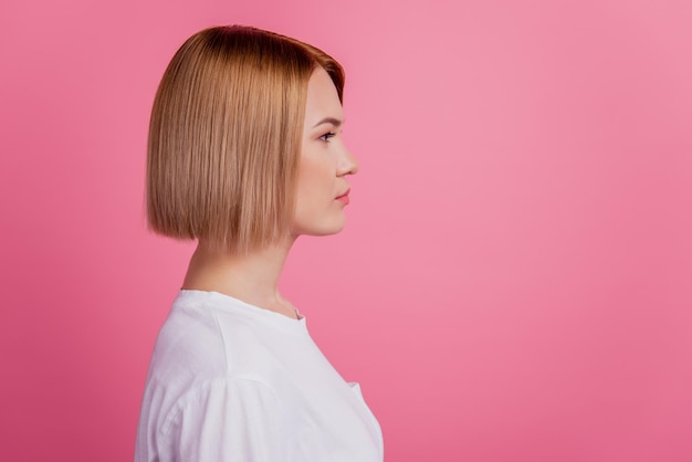 차분한 자신감 있는 여성의 프로필 사진은 분홍색 배경에 격리된 흰색 티셔츠를 입고 빈 공간을 보입니다.