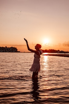 Profile photo of woman splashing water silhouette of beautiful happy slender blonde in a summer dres...