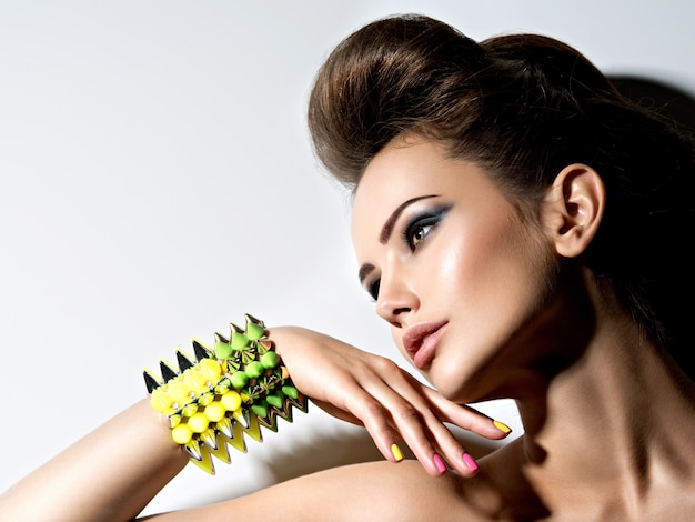 Profile portrait of a Beautiful  woman wearing bracelet with thorns and mulricolored nails