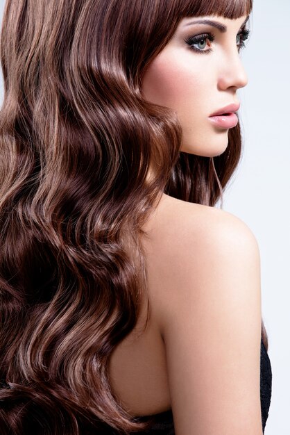 Profile portrait of a beautiful woman with brown curly hairs - isolated on white background.