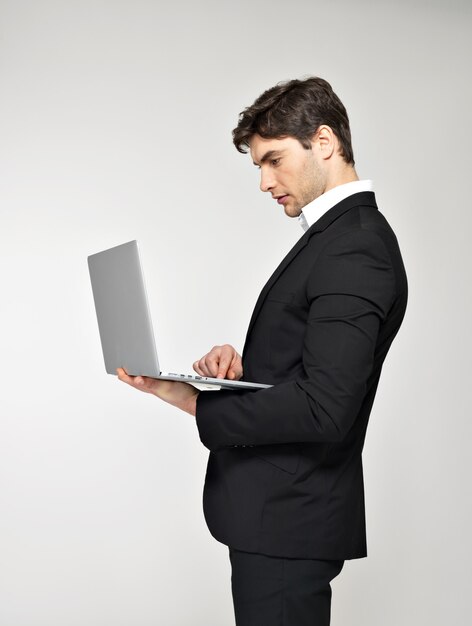 Profile portrait of businessman working on laptop in black suit