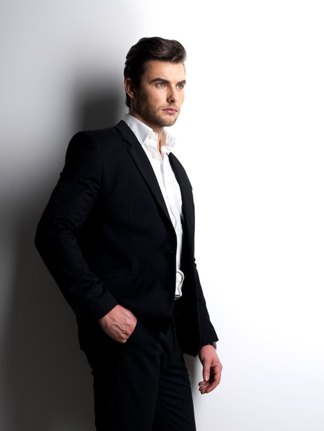 Profile portrait of a Fashion young man in black suit posing at  studio