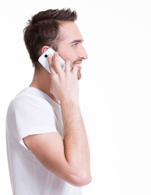 Профиль портрет счастливого человека, вызывающего мобильным телефоном в повседневной одежде - изолированный на белом. Концепция коммуникации.