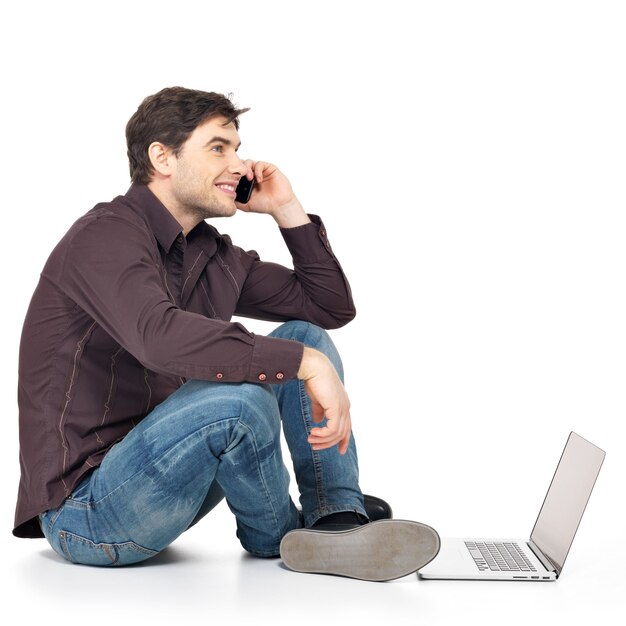 Profile portrait of man calling on phone with laptop isolated on white.