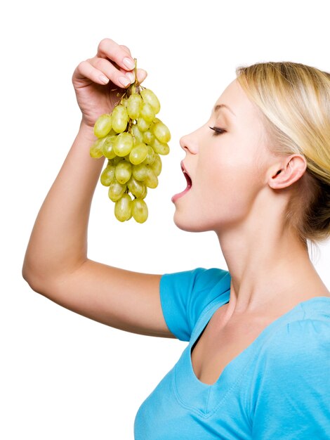 Profile portrait of a young female with sweet grape - isolated on white