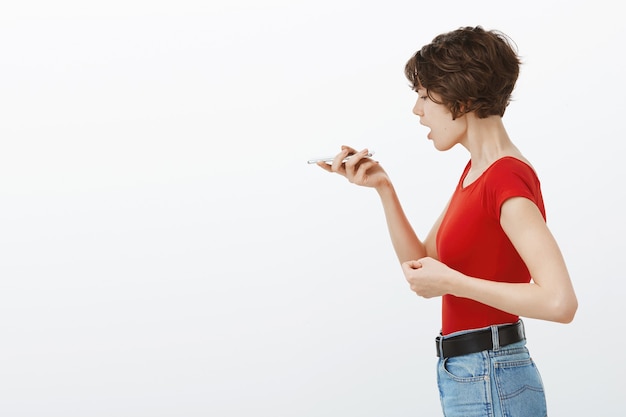 電話レコーダー、スマートフォンで音声メッセージを使用して若いスタイリッシュな女性のプロフィールの肖像画