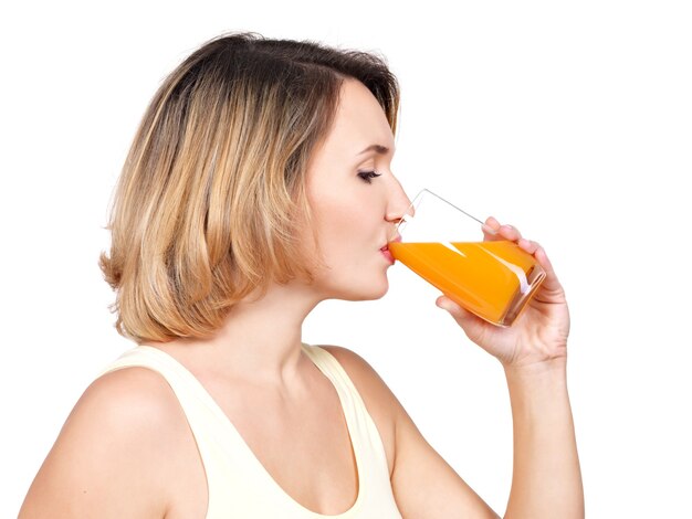 Profile portrait of a young woman drinks  orange juice isolated on white.