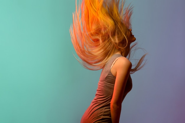 Foto gratuita profilo di giovane donna bionda graziosa che scuote i suoi capelli