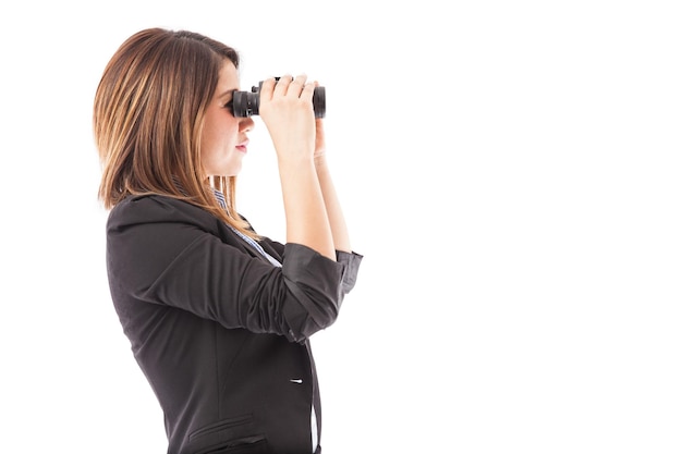 Foto gratuita vista di profilo di una donna d'affari che guarda attraverso il binocolo che rappresenta una ricerca di lavoro. un sacco di spazio per la copia