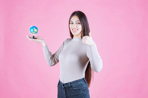 Profile view of a girl holding a mini globe with confidence